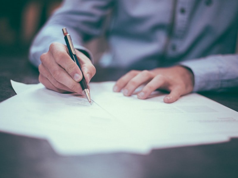 Person signing documents with a pen at a desk