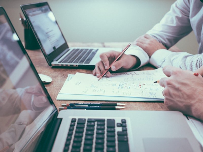 Investor reviewing financial documents and a laptop at a desk